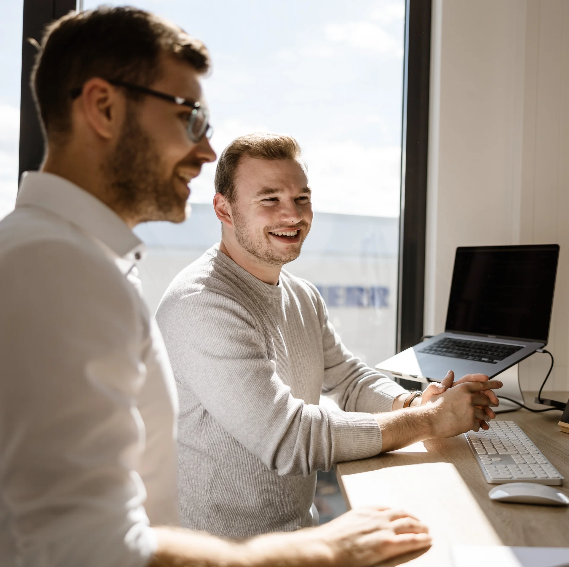 Zwei LightsOn Mitarbeiter stehen am Schreibtisch und schauen in den Monitor