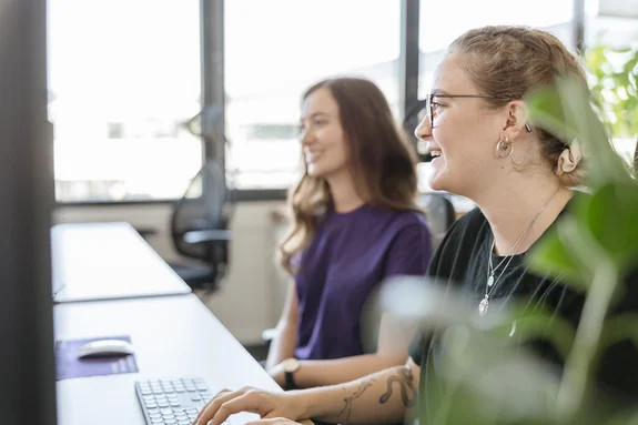 Zwei LightsOn Mitarbeiterinnen sitzen am Schreibtisch und schauen in den Bildschirm