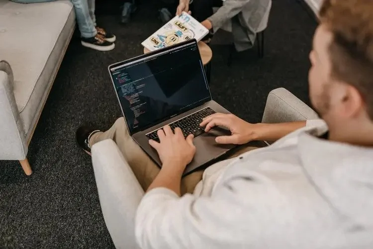 Mann arbeitet an seinem Laptop auf seinem Schoß