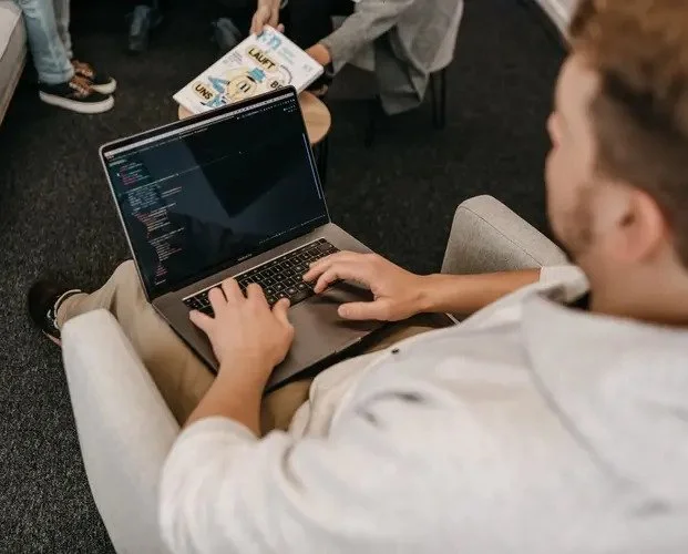 Mann arbeitet an seinem Laptop auf seinem Schoß