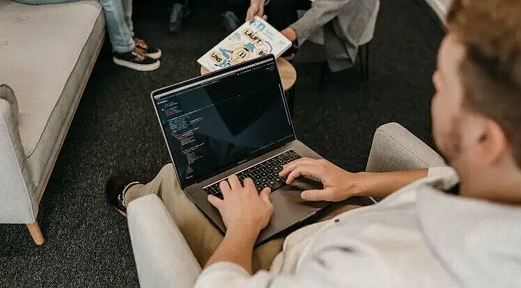 Mann arbeitet an seinem Laptop auf seinem Schoß