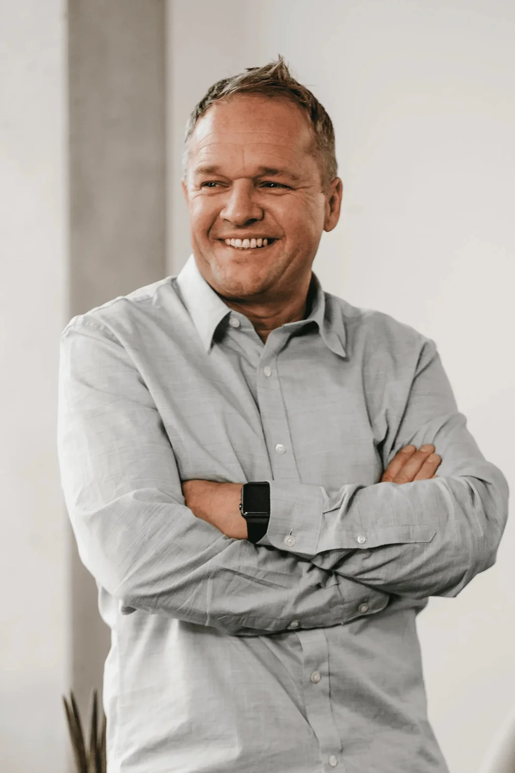 Michael Auger posiert lachend vor grauer Wand