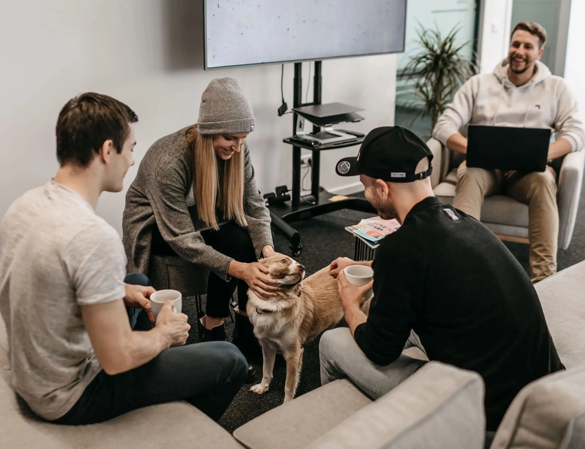 Vier Personen sitzen in einer Sitzecke mit einem Hund in der Mitte