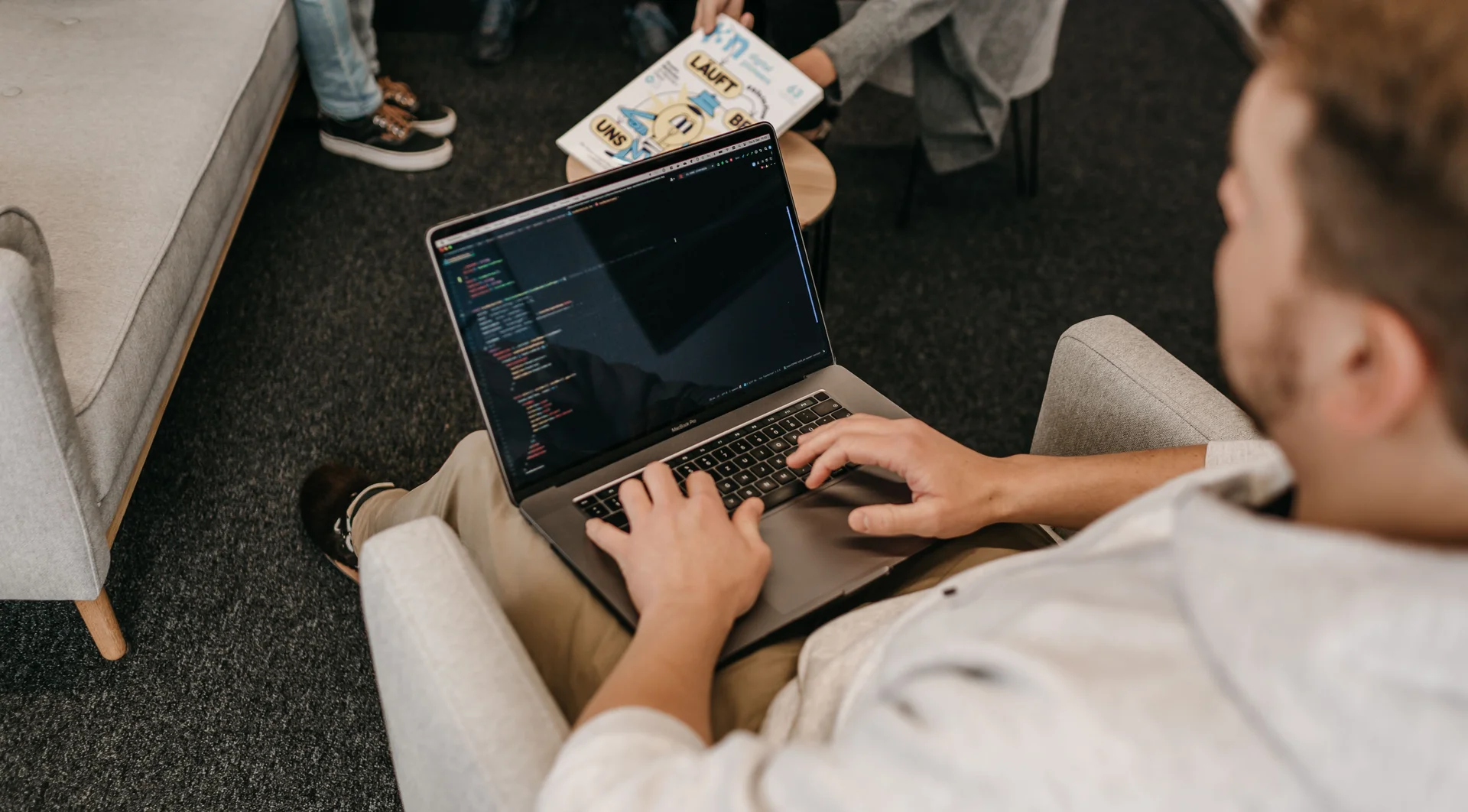 Entwickler arbeitet auf einem bequemen Sessel mit Laptop auf dem Schoß