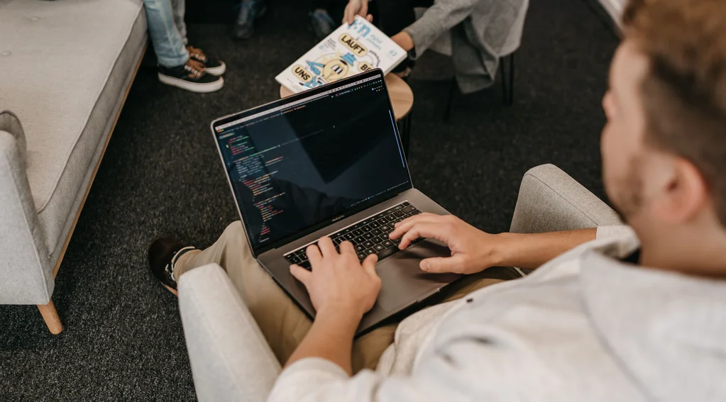 Entwickler arbeitet auf einem bequemen Sessel mit Laptop auf dem Schoß