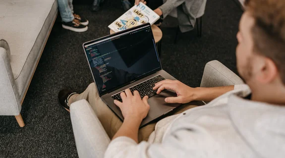 Entwickler arbeitet auf einem bequemen Sessel mit Laptop auf dem Schoß