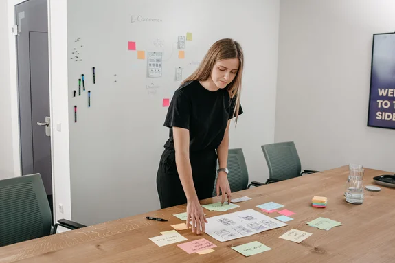 LightsOn Mitarbeiterin sortiert PostIts auf einem Tisch im Konferenzraum