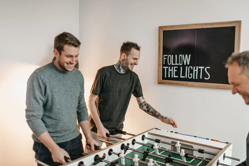 drei Personen spielen Tischkicker