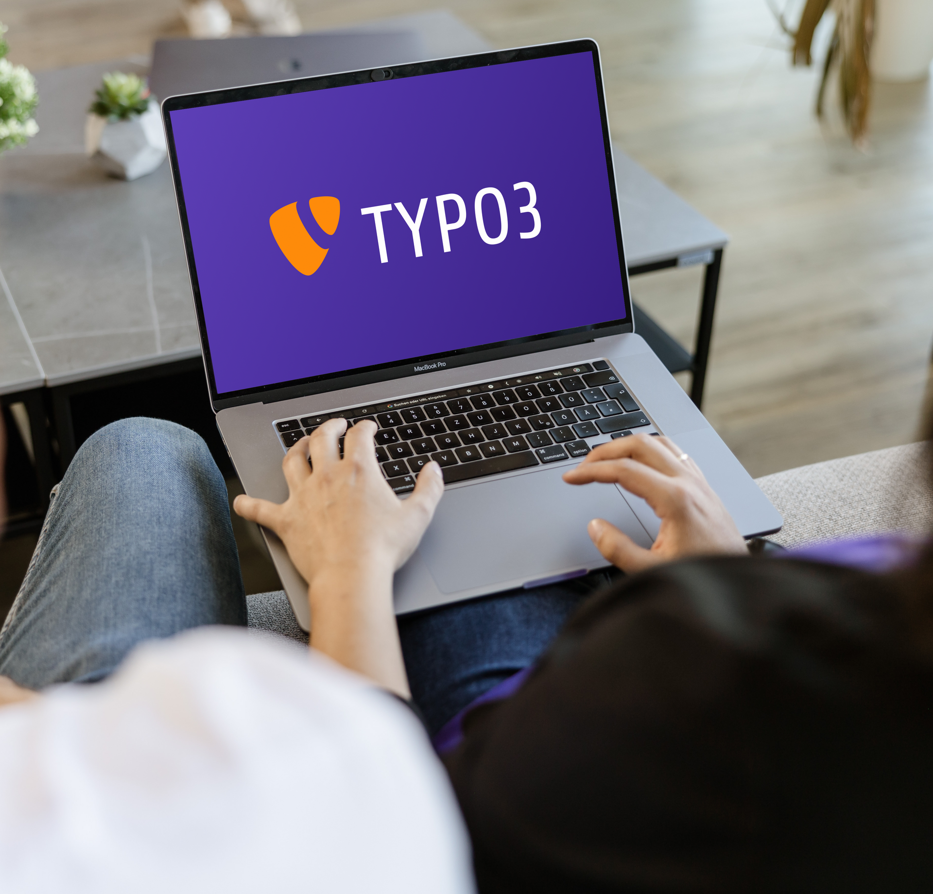 Zwei Mitarbeiter schauen in Laptop auf dem TYPO3 auf dem Monitor steht