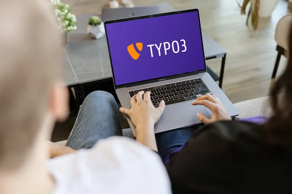 Zwei Mitarbeiter schauen in Laptop auf dem TYPO3 auf dem Monitor steht